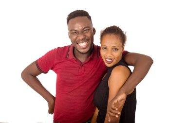 Genç ve çekici bir çift gülümsüyor ve sarılıyor. Bu arada erkek beyaz arka planda kız arkadaşına sarılıyor.