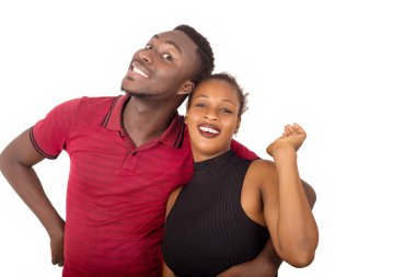 Genç ve çekici bir çift gülümsüyor ve sarılıyor. Bu arada erkek beyaz arka planda kız arkadaşına sarılıyor.