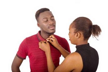 Kadın, erkek arkadaşının kıyafetlerini ayarlıyor. Kadın, beyaz arka planda kocasının giyinmesine yardım ediyor..