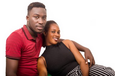 Beyaz bir arka planda oturan bir çift kameraya bakıp gülümsüyor..