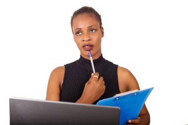 Genç kendine güvenen sekreter ya da ofis müdürü ofisinin önünde oturuyor ve iş planını laptopunun önünde yazıyor.