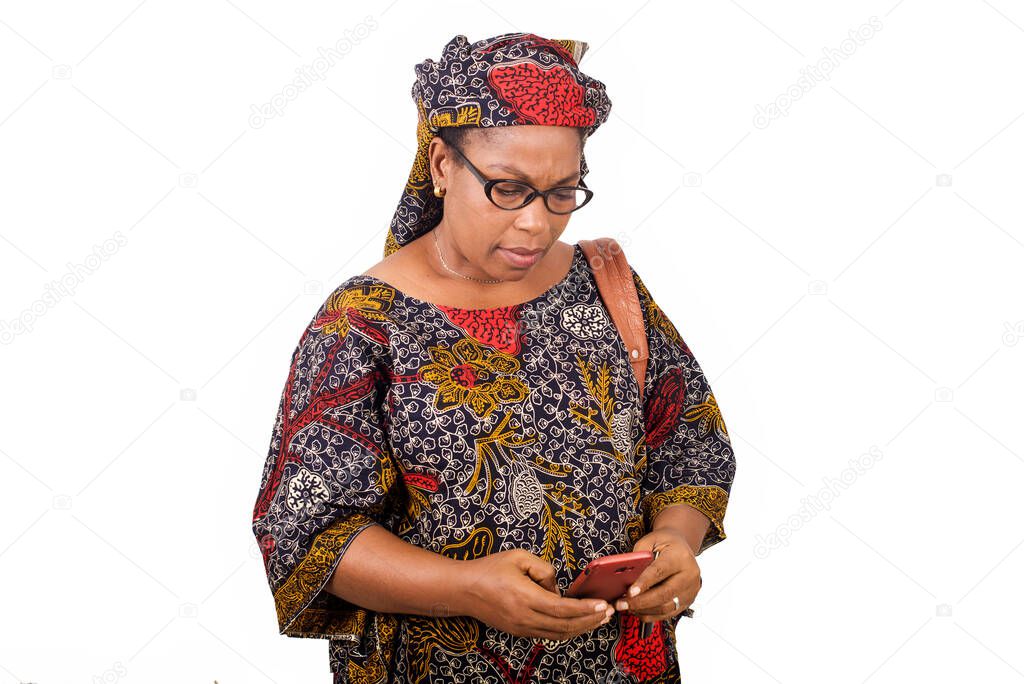 african mature woman in loincloth standing on white background looking at mobile phone.