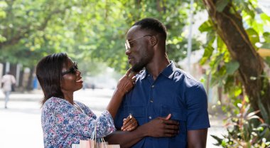 Genç bir kadın alışveriş yaptıktan sonra erkek arkadaşına sarılıp gülümsüyor..