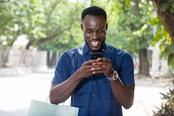 Молодий Чоловік Стоїть Відкритому Повітрі Сумкою Покупок Збирається Дивитися Мобільний — стокове фото