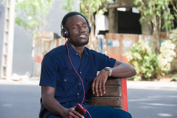 Jovem Ouve Música Com Fones Ouvido Enquanto Senta Uma Cadeira — Fotografia de Stock