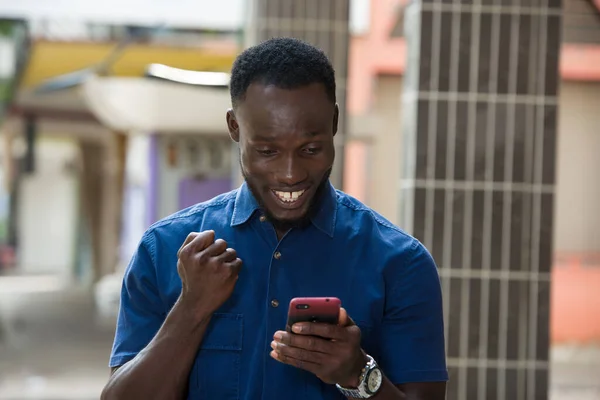 Jeune Homme Debout Extérieur Regardant Téléphone Mobile Tout Souriant — Photo