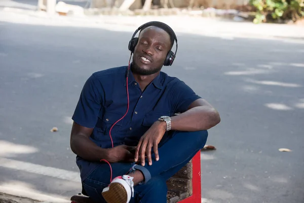 Mladý Muž Poslouchá Hudbu Sluchátky Zatímco Sedí Venku Židli Poslouchá — Stock fotografie
