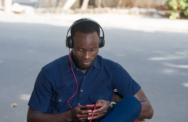 Genç Adam Dışarıda Oturmuş Kulaklıkla Cep Telefonuyla Konuşuyor — Stok fotoğraf