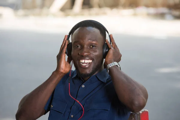 Genç Adam Dışarıda Oturmuş Kulaklıkla Müzik Dinliyor Gülümseyen Kameraya Bakıyor — Stok fotoğraf