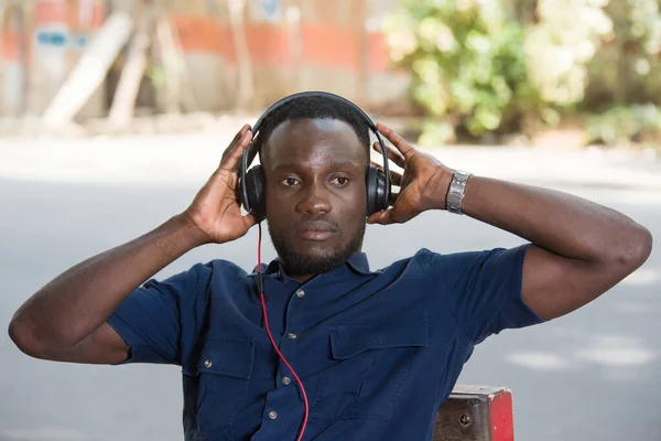 Mladý Muž Sedí Židli Poslouchá Hudbu Sluchátky Venku — Stock fotografie