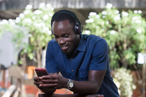 Man listens to music with headphones using a mobile phone outdoors.