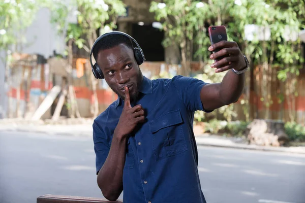 Muž Poslouchá Hudbu Sluchátky Pomocí Mobilu Dělá Fotografie Gestem Ticha — Stock fotografie