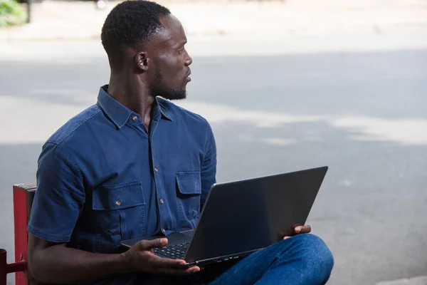 Młody Człowiek Siedzi Zewnątrz Laptopem Oglądając Coś Zaskoczonego — Zdjęcie stockowe
