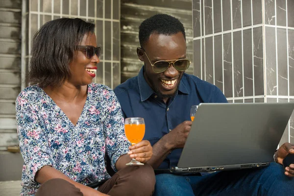 handsome man with laptop and smiling girl with shopping bag sitting outside in city uses laptop laughing.