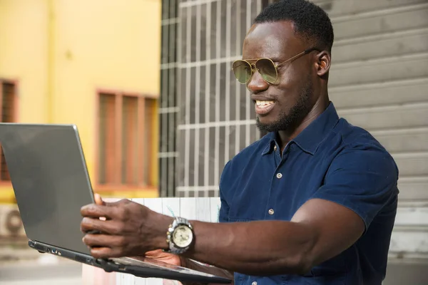 Młody Człowiek Siedzi Zewnątrz Patrząc Laptopa Uśmiechnięty — Zdjęcie stockowe