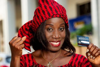 Şehre alışverişe giden mutlu bir kadın, güneşli bir günde kameraya bir kredi kartı sunar. Satış, tüketim ve insan konsepti.