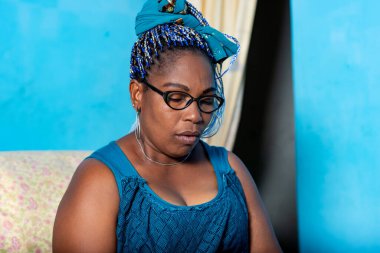 Mavi peştamallı güzel, olgun bir Afrikalı kadın oturuyor. Koltuğunda gözlerini kapatırken rahatlamaya gidiyor.