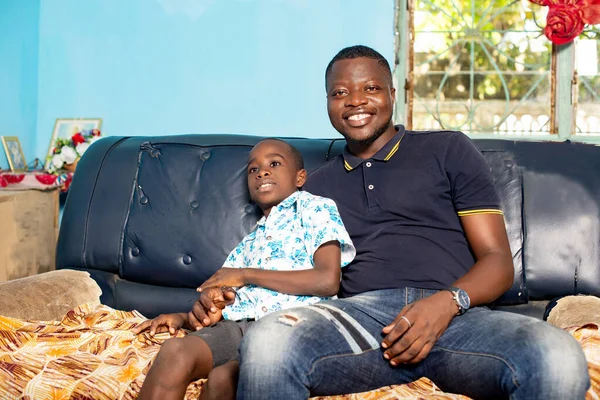Africano Pai Seu Filho Sentado Mesma Poltrona Estão Sorrindo Juntos — Fotografia de Stock
