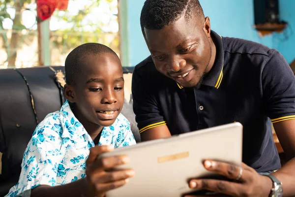 Africký Dospělý Otec Ukazující Věc Digitálním Tabletu Svému Synovi Jak — Stock fotografie
