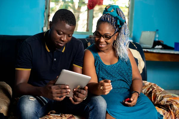 Hermosa Pareja Africana Sentada Sofá Está Viendo Tableta Digital Mientras —  Fotos de Stock