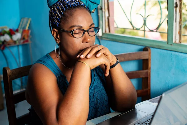 Gözlüklü olgun bir kadın dizüstü bilgisayarla oturma odasında oturuyor ve düşünüyor..