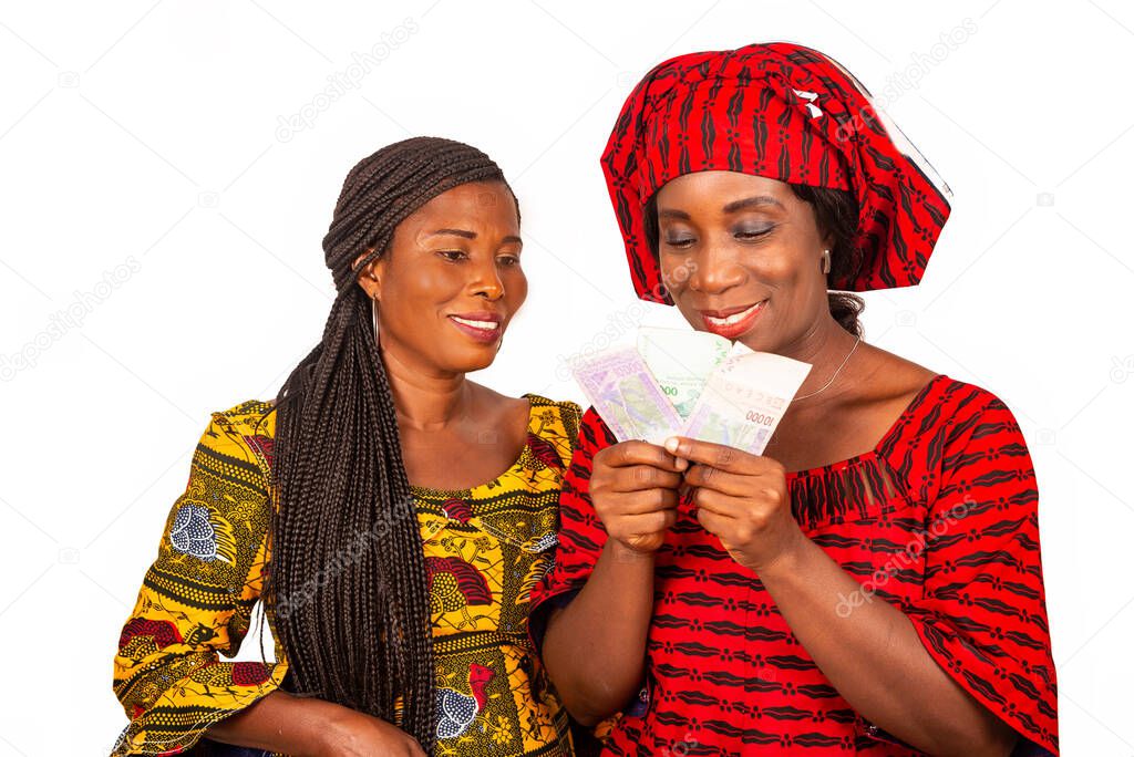 two beautiful businesswomen standing in traditional dress on white background looking at bank notes smiling.