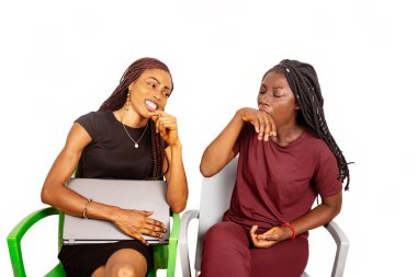 İki güzel kız kardeş bir sandalyede oturuyor ve gülümserken dizüstü bilgisayarlarını tutuyorlar.