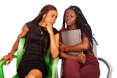 İki genç Afrikalı öğrenci sandalyede oturup dizüstü bilgisayarla konuşuyor.