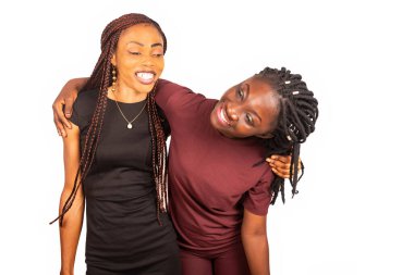 Beyaz arka planda yapayalnız duran iki genç kadın sarılıp gülüyor..