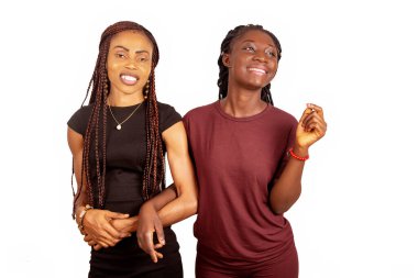 İki güzel kız yan yana durmuş, sırıtıyorlar.