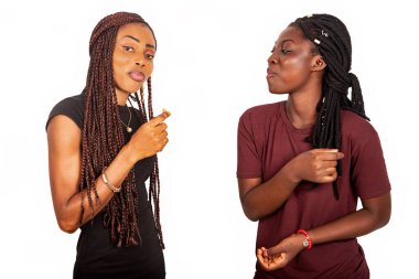 İki güzel Afrikalı kız arkadaş, örgü örmüş ellerinde kurabiyelerle beyaz arka planda izole bir şekilde gülümseyerek duruyorlar.