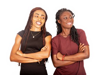 İki güzel kız kardeş ayakta ve kollarını kavuşturup yan yana bakıyorlar.