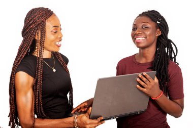 İki gülümseyen güzel kız kardeş koyu siyah ve kırmızı renklerde dizüstü bilgisayar tutuyorlar.