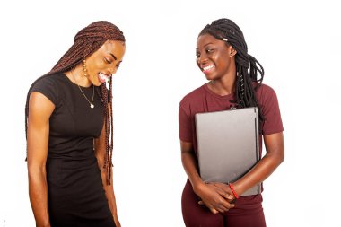 Beyaz arka planda duran iki güzel öğrenci ellerinde dizüstü bilgisayarla gülüyorlar..