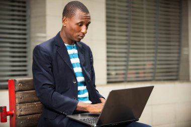 Yakışıklı, ciddi bir iş adamı iş merkezinin yanında dizüstü bilgisayar kullanıyor.