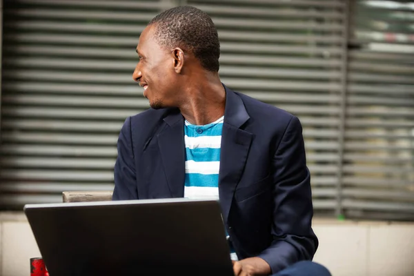 Przystojny Mężczyzna Siedzi Ławce Pobliżu Firmy Pomocą Laptopa Patrząc Bokiem — Zdjęcie stockowe