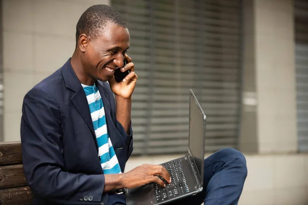Obraz Szczęśliwego Młodego Biznesmena Siedzącego Zewnątrz Ławce Korzystającego Laptopa Rozmawiającego — Zdjęcie stockowe