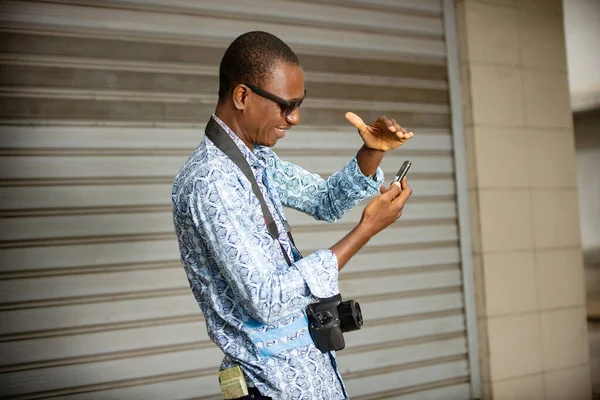 Bonito Jovem Fotógrafo Africano Lateralmente Usando Telefone Celular Enquanto Sorri — Fotografia de Stock