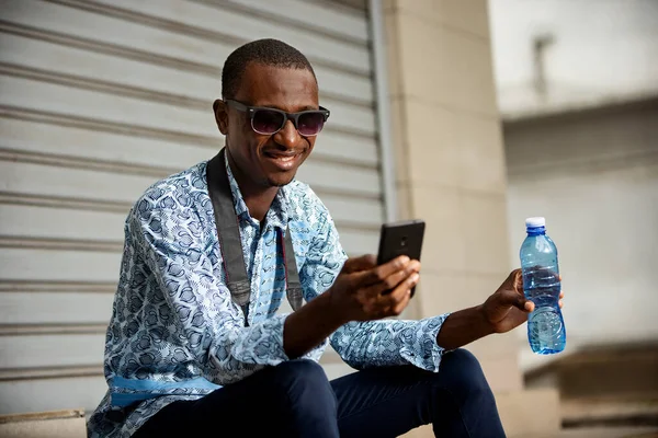 Bonito Jovem Fotógrafo Africano Vestindo Uma Camisa Jeans Usando Telefone — Fotografia de Stock