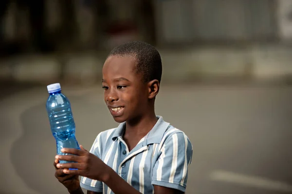 可愛いアフリカ人の男の子が笑顔でペットボトルを見て — ストック写真