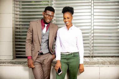 Ciddi iş adamları sokakta durup kameraya bakıp gülümsüyor.