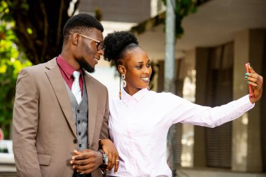 Sokakta yürürken gülümseyerek selfie çeken güzel bir Afrikalı çiftin portresi.