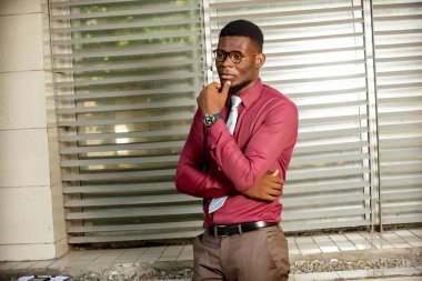 Kırmızı bir bordo kimyasalı, siyah bir saat ve gözlük takan Afrikalı genç bir adamın portresi yansıması..