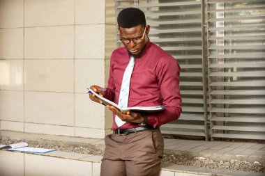 Yakışıklı, genç, modern bir işadamı elinde bir kayıt defteriyle caddede yürüyor.