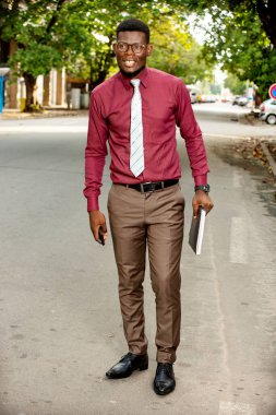 Yakışıklı, genç, modern bir işadamı elinde kırmızı bordo pantolon ve kırmızı kaşmir ile elinde bir kayıt defteriyle sokakta yürüyor.