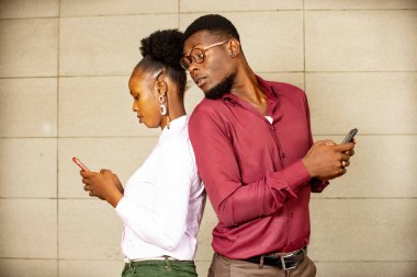 Elinde telefon olan meraklı bir adam karısının cep telefonuna bakıp bir mesaj yazıyor.