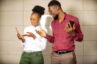 Güzel bir kadın dışarıda duruyor ve kocasına gülümsemesini göstermek için telefon ekranını işaret ediyor.