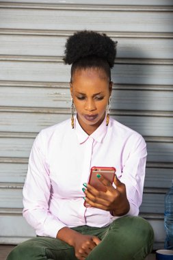 Güzel, genç bir Afrikalı kadın oturuyor ve cep telefonuyla video görüşmesi yapıyor.