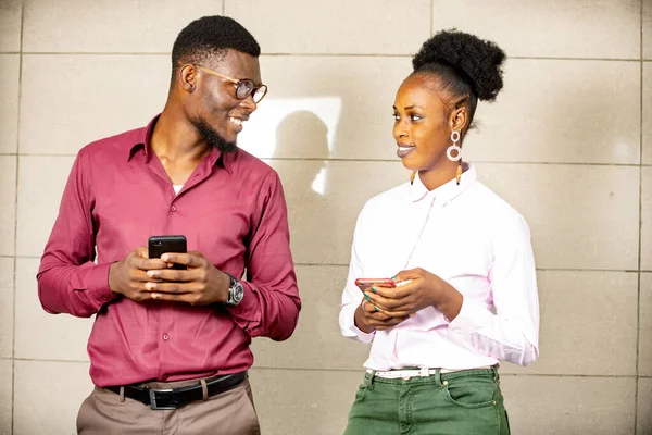 Man Woman Standing Each Holding Phone Looking Each Other Smiling — Stock Photo, Image