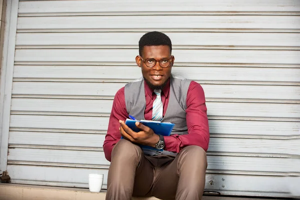 Молодий Африканський Бізнесмен Сидячи Зовні Блокнотом Дивлячись Камеру Посміхаючись — стокове фото